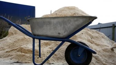 Ağaç talaşları bir kepçe kepçeyle bir bahçe arabasına dökülüyor. Yığınla taze, kuru çam talaşı. Kereste fabrikasında ahşap atığı üstüne ahşap atığı.