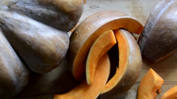 Meloun, rozsekaný na kusy, leží na dřevěné desce. Dýňové plátky na řezací desce. Vaření zeleniny pro zdravou stravu — Stock video