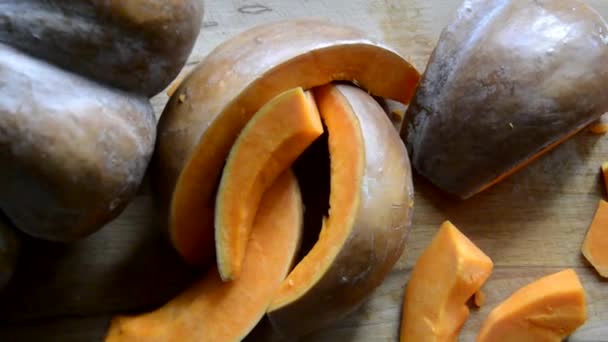 Fatias de abóbora laranja são tomadas em close-up. Melão, cortado em pedaços, está em uma tábua de corte de madeira — Vídeo de Stock