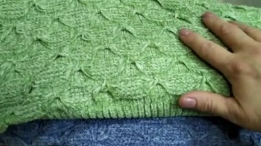 Örgü kumaşı elle okşuyorum. Ilık örülmüş şeyler. Örülmüş süveterler yığının içinde..