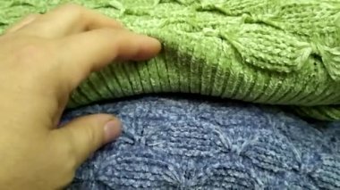 Örgü kumaşların el dokunuşları. Örgü süveterler yığının içinde katlandı. Sıcak örülmüş şeyler..