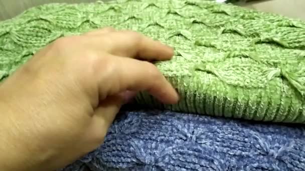 Teplé pletené věci. Ruka hladí pletenou látku. Pletené svetry složené na hromadě. — Stock video