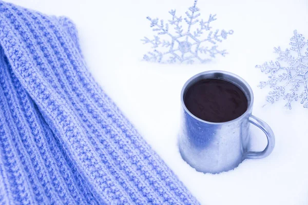 Coffee in an old metal mug in the snow. Christmas toys in the form of snowflakes and a hand-knitted lilac scarf. New year\'s composition for Christmas with the text 2021.