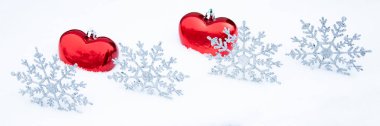 Karda bir çift kalp ve kar tanesi. Kırmızı kalpli, karlı bir Noel arkaplanı. Noel panoramik arka planı.