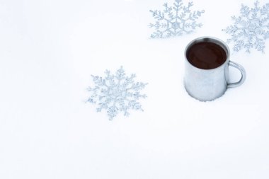 Kar taneleri ve karda bir kupa sıcak kahveyle Noel arkaplanı. Sokakta kahve içen eski bir metal bardağın etrafında kar taneleri..