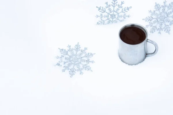 Kar taneleri ve karda bir kupa sıcak kahveyle Noel arkaplanı. Sokakta kahve içen eski bir metal bardağın etrafında kar taneleri..