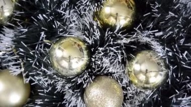 Yeşil karla kaplı köknar çelengi üzerinde bir demet altın parıltı ve mat Noel topları saat yönünde yavaşça dönüyor. Noel kış arkaplanı. Mutlu yıllar..