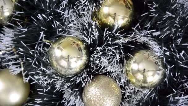 Un montón de bolas doradas y brillantes de Navidad mate en una guirnalda de abeto cubierta de nieve verde giran lentamente en dirección de las agujas del reloj. Fondo de invierno de Navidad. Feliz Año Nuevo. — Vídeos de Stock