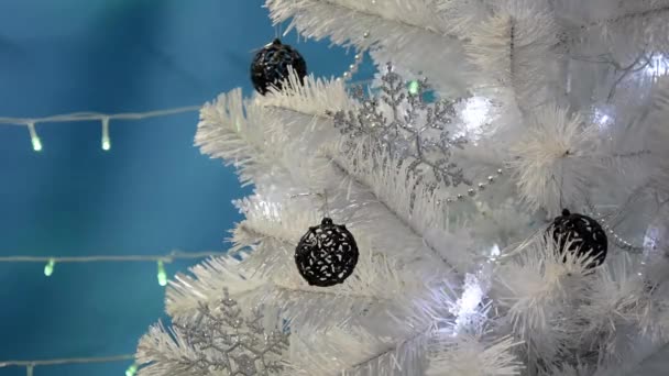 Різдвяна ялинка прикрашена сріблястими сніжинками та чорними рибальськими кульками. Різдвяна ялинка з блимаючими вогнями та різдвяними іграшками на синьому фоні. Різдвяний фон. З Новим роком . — стокове відео