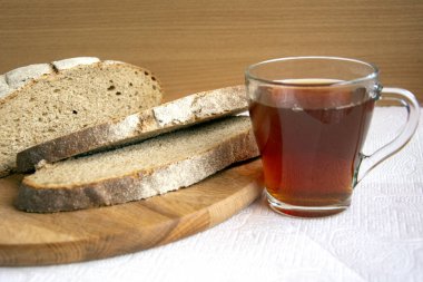 Ekmek ve bir fincan çay. Ekmek dilimleri ve bir bardak koyu çay. Taze aromatik çavdar ekmeği, parçalara ayrılmış..