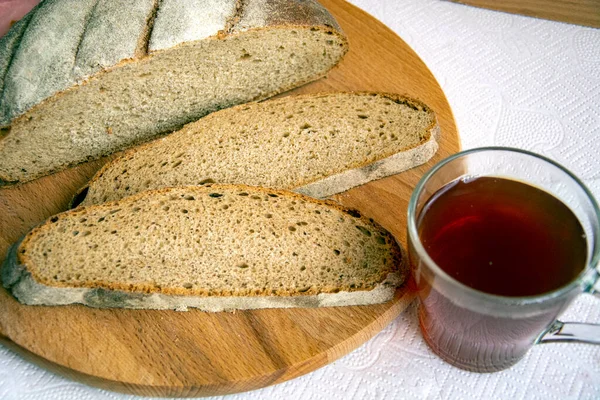 Bread and a cup of tea for breakfast. Slices of bread and a glass of strong tea close-up. Fresh aromatic rye bread, cut into pieces.