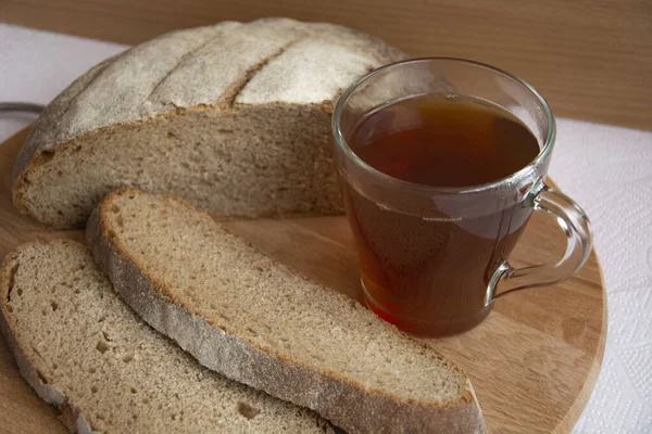 Bread and tea for breakfast. Slices of bread and a glass of strong tea close-up. Freshly baked aromatic rye bread, cut into pieces.