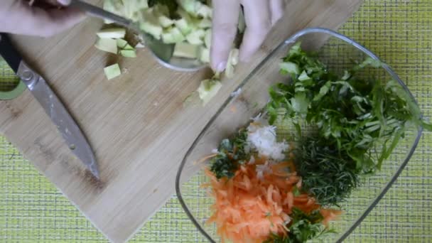 Egy nő egy tál salátába teszi a szeletelt avokádót. Étrendi főzés. — Stock videók