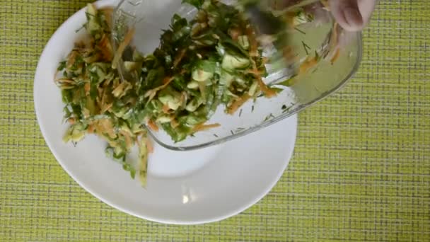Den zubereiteten Gemüsesalat legt die Frau auf einem weißen Teller aus. Kochen diätetischer Mahlzeiten. — Stockvideo