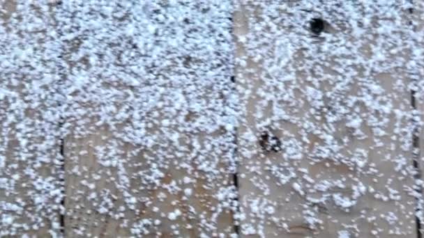 Sněhové vločky na prknech. Na dřevěné verandě leží zrnka sněhu. Padal první sníh. Zasněžená podlaha. — Stock video