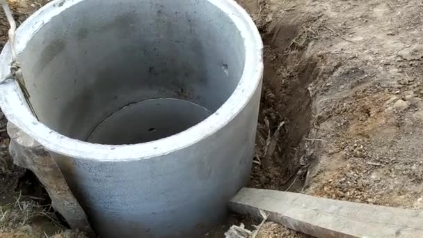 Installation d'anneaux en béton pour l'assainissement près de la maison. Amélioration des terres. Travaux de construction pour l'installation d'égouts. — Video