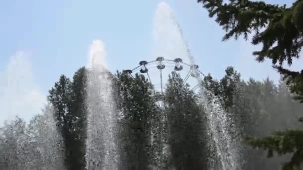 Fuente antigua en el parque de la ciudad en verano. Los chorros de agua de la fuente brillan sobre el fondo del anillo de la fortuna. — Vídeo de stock