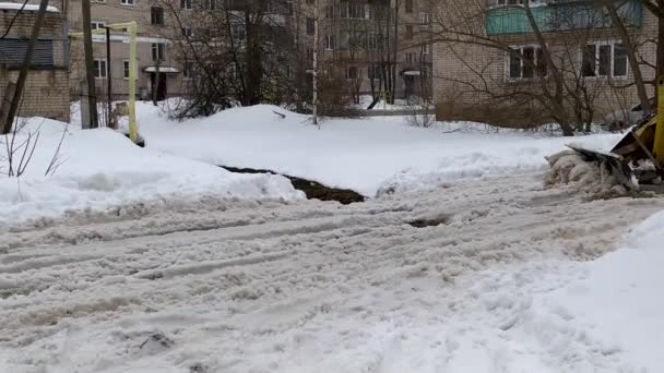 Le tracteur nettoie la route de la neige et de la boue. Travaux d'aménagement urbain. Nettoyage routier. — Video