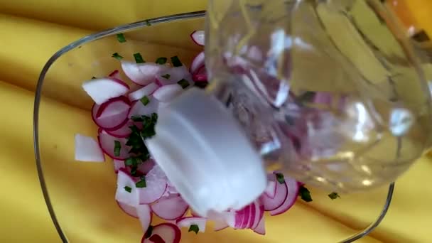 Rettichsalat wird mit Sonnenblumenöl übergossen. Vitaminsalat aus Radieschen und Kräutern in einer Glasschüssel. — Stockvideo