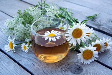 Papatya çayı. Yaz aylarında kır çiçekleri ve papatya çaylarıyla dolu cam bir bardakta içmek. Çiçek arka planı.