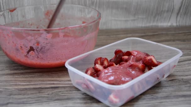 Le bacche di fragola sono versate con purè di fragole, raccogliendo per l'inverno in contenitori. Fragole mature montate con un frullatore in un piatto di vetro su una tavola di legno. — Video Stock