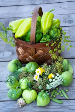 Ahşap bir arka planda sepetteki sebzeler. Taze sebzeli sepetler, dereotu ve bir buket kır çiçeği. Domates ve biber hasat ediyorum..