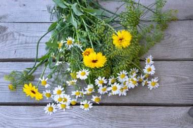 Bouquet of flowers on a wooden background. Wildflowers lie on the boards. Chamomile and daisies.