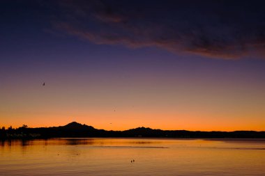 Baker Dağı ve Washinton 'daki Üç Kız Kardeş, Kanada' daki White Rock rıhtımından gelen sıcak bir kış günışığının gölgesiyle gölgelenmiştir.