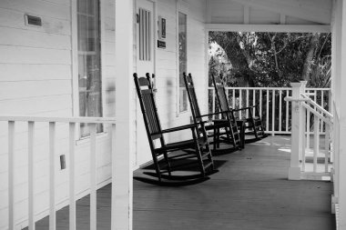 Serin, beyaz verandada üç siyah sallanan sandalye. Kıyı Keşif Müzesi, Hilton Head Adası