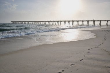 Pensacola sahilindeki gelgit, Florida 'nın Panhandle sahilindeki Pensacola İskelesi' ne doğru yeni ayak izleri için taze kum bırakıyor.