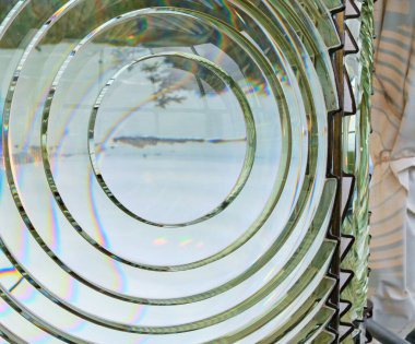 Close-up of Fresnel lens at Oregon's Cape Blanco Lighthouse showing inverted image of foggy coast...islands and trees... and colorful splashes due to refraction clipart