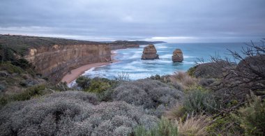 Yavaş deklanşör hızı bulutlu bir sabahta şafak sökerken Avustralya 'nın 12 havarisinin etrafında sörf yapıyor.