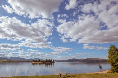 Jindabyne Gölü 'nün sakin suları ve güzel beyaz kümülüs bulutu ve mavi gökyüzü, NSW, Avustralya