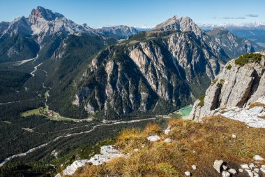 Dikey bir düşüşe yakın çekilen dramatik görüntü, ormanlık vadiye ve İtalyan Dolomitleri 'ndeki diğer tepelere bakıyor.