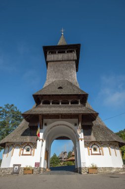 Looking through unique entrance with very high, wooden shingle roofed tower to the grounds of Barsana Monastery, Maramures, Romaina