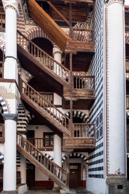 Wooden staircase gives access to residence areas of Rila Monastery, Bulgaria.  Characteristic stripes of the complex architecture appear in several forms.