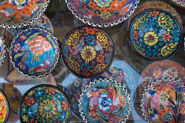 Assortment of bright, colorful, glazed pottery bowls for sale in souvenir shop, Bulgaria.  Patterns include flowers, dots and leaves.