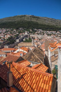 Önünde Dubrovnik 'in eski kasabasının eski kiremitli çatıları olan dikey manzara, şehrin ortasında yer alan Şehir Duvarları ve arka planda Srd Dağı. Hırvatistan