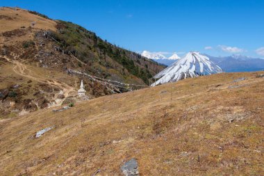 Bayraklar, deniz seviyesinden 3988 m (13084 ft) yüksekteki Bhutan 'ın Chele La geçidinde dalgalanmaktadır. Jumolhari 'nin 7 314 m (23 996 ft) ve Jichu Drake' in 6 794 m (22 290 ft) yüksekliğindeki karlı zirveleri ufukta görünür.