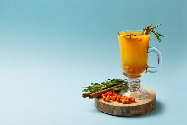 Sea buckthorn drink with rosemary in glass on blue background, copy space, top view