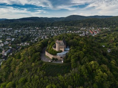 Yeşillik ve arka planda küçük bir kasaba ile çevrili bir ortaçağ şatosunun havadan görünüşü.