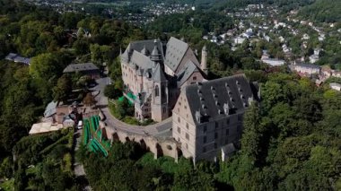 Çevresi yeşillik ve kasabayla çevrili tarihi bir şatonun havadan görünüşü.
