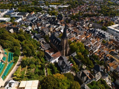 Geleneksel binalar ve yemyeşil alanlarla çevrili seçkin bir kilise kulesine sahip tarihi bir Avrupa kasabasının havadan görünüşü.