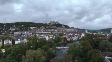 Nehir, tepeler ve şatosu olan bir Avrupa kasabasının havadan görünüşü.