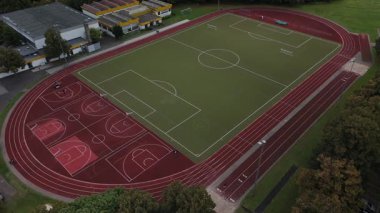Futbol sahası, koşu sahası ve basketbol sahası olan bir spor kompleksinin havadan görünüşü..
