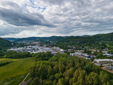 Şehir ve tepeleri olan yemyeşil bir vadinin havadan görünüşü.