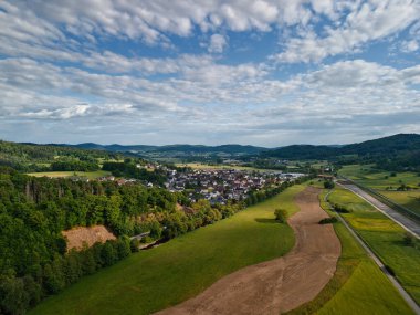 Şehir ve tepeleri olan yemyeşil bir vadinin havadan görünüşü.
