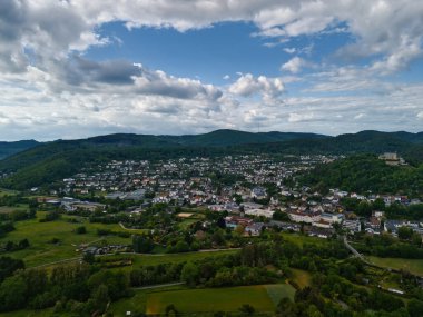 Şehir ve tepeleri olan yemyeşil bir vadinin havadan görünüşü.