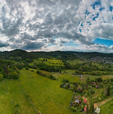 Şehir ve tepeleri olan yemyeşil bir vadinin havadan görünüşü.