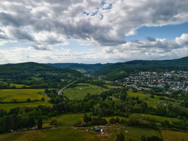 Şehir ve tepeleri olan yemyeşil bir vadinin havadan görünüşü.
